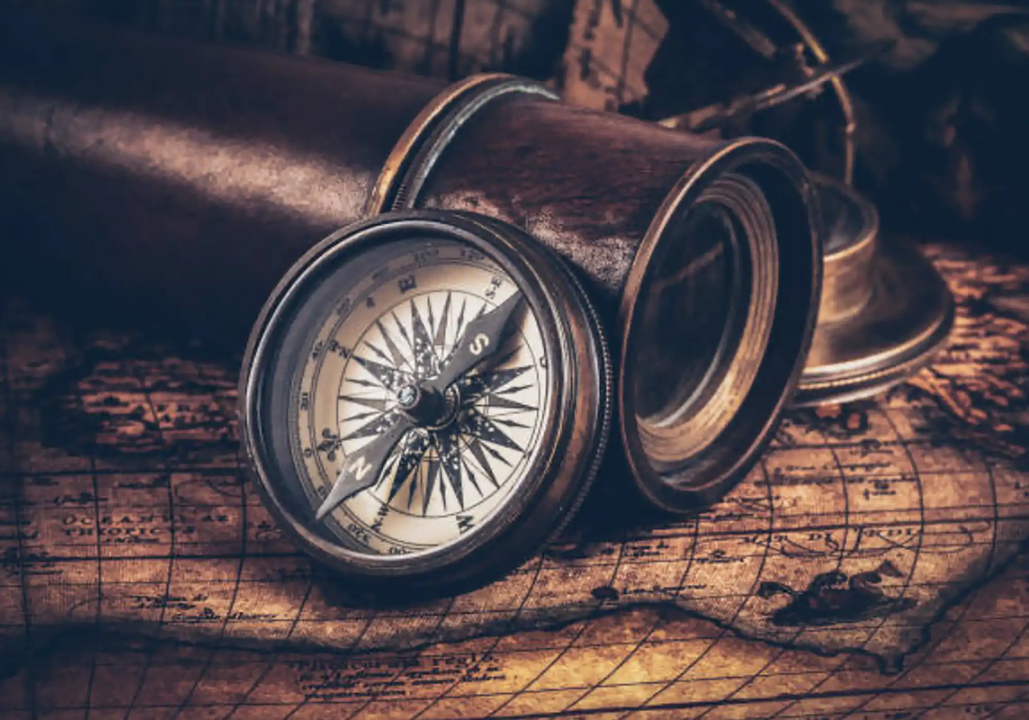 Vintage Kompass und Fernglas auf einer alten Landkarte, Symbol für Orientierung, Fokus und Konzentration im Alltag