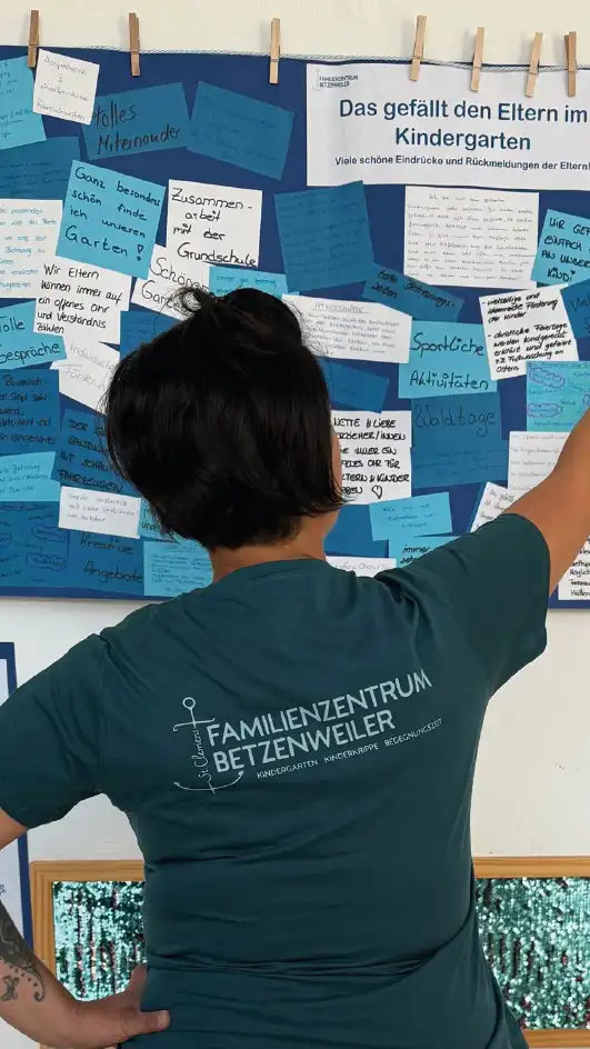 Kindergarten Familienzentrum Kindergartenleitung an Pinnwand mit neuem Shirt mit Ideenfindung Familienzentrum im Austausch